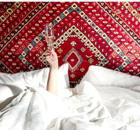 A woman laying in bed with a glass of wine